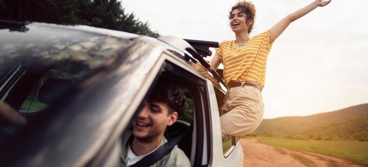 Girl hanging out car window smiling now she has broken up with her bad spending habits.